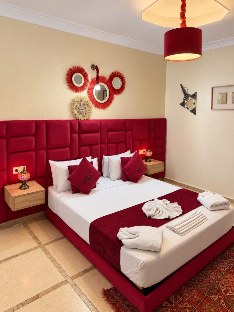 Détails de la chambre Mérinides, coussins rouges et lampes de chevet
