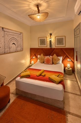 Chambre Almohades au Riad Dar Chadia : lit double, tête de lit terracotta et décoration marocaine.