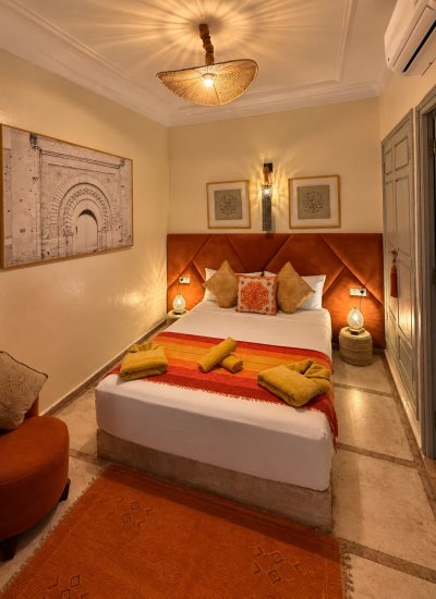 Chambre Almohades au Riad Dar Chadia : lit double, tête de lit terracotta et décoration marocaine.