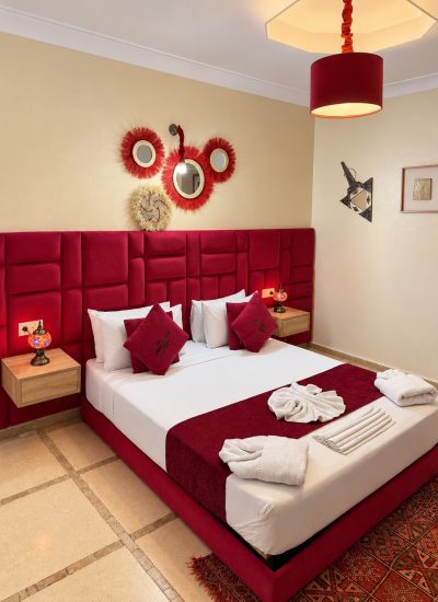 Détails de la chambre Mérinides, coussins rouges et lampes de chevet