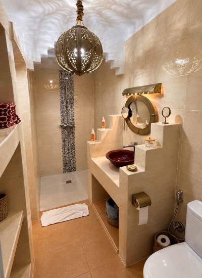 Salle de bains de la chambre Saadiens avec douche, vasque bordeaux et lanterne